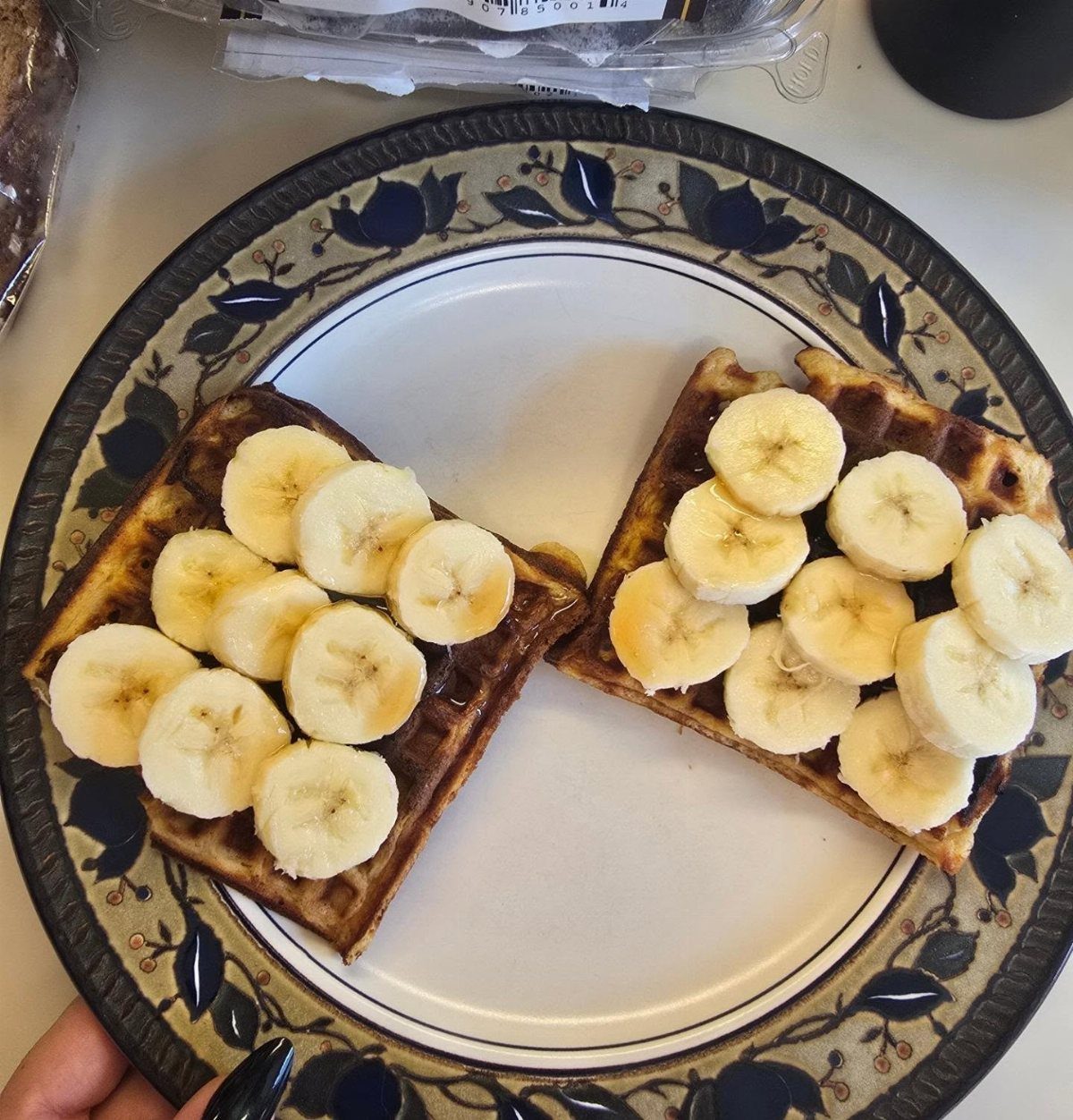 32 Ideas on What to Serve for Breakfast, From Eggs to Scones 9 Two toasted waffles topped with fresh banana slices on a blue floral plate.