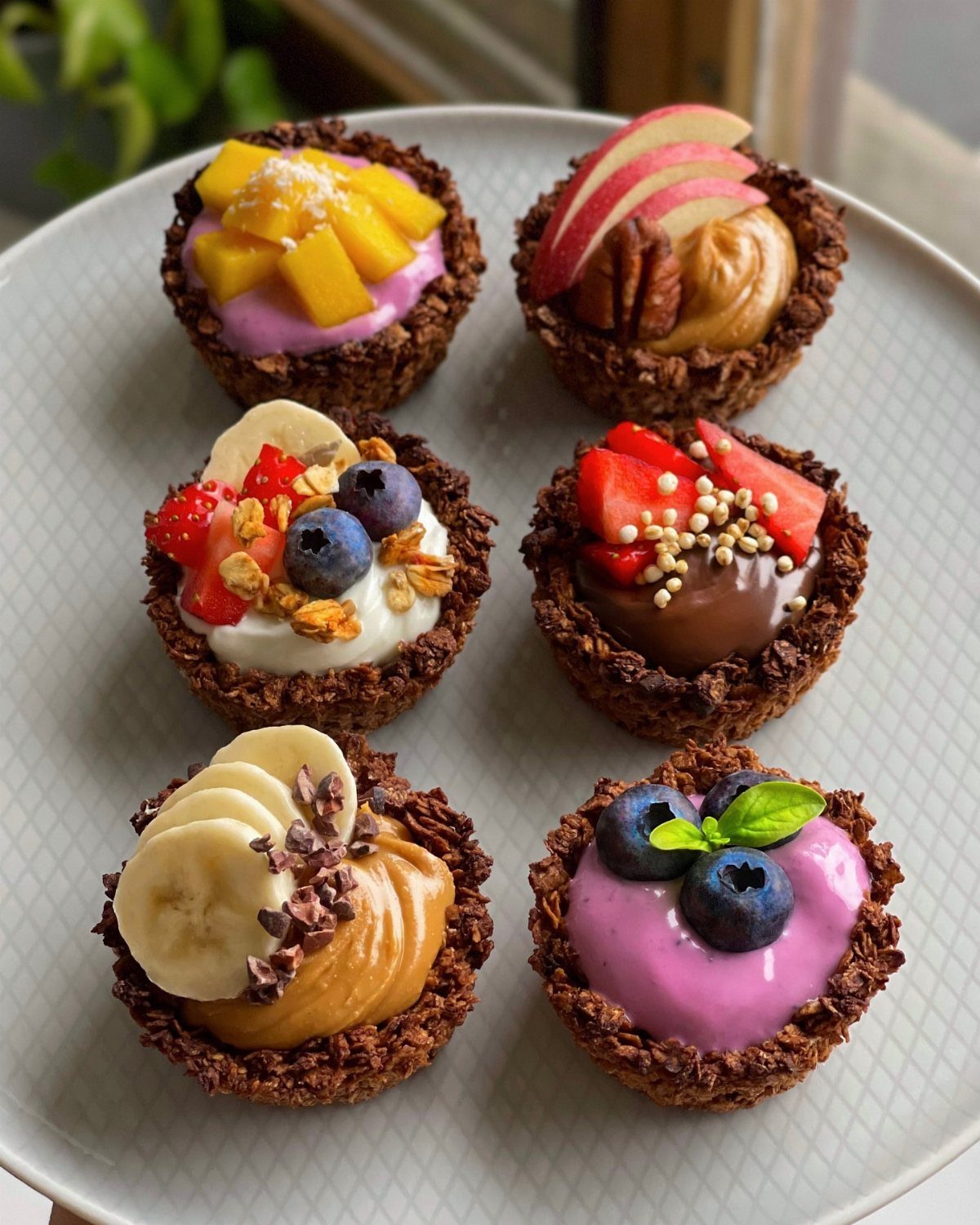 32 Ideas on What to Serve for Breakfast, From Eggs to Scones 29 Six granola cups filled with colorful yogurt, fresh fruits, and nuts on a plate.